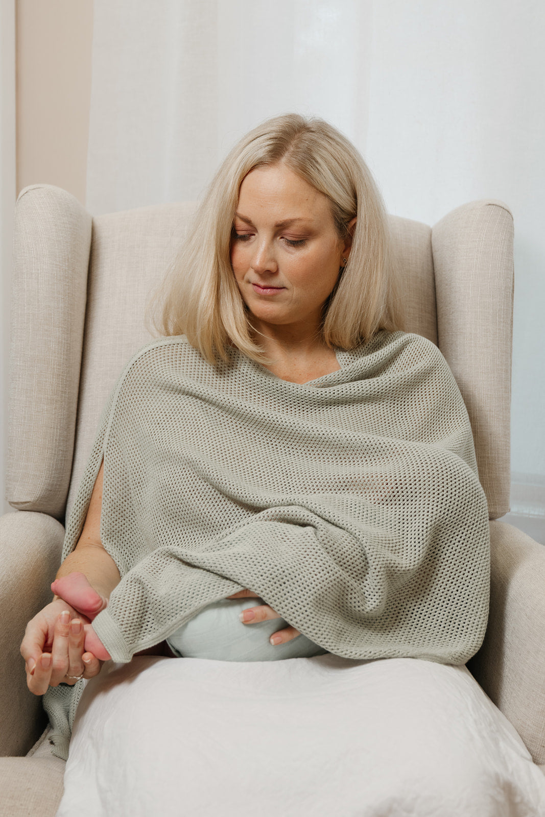 mother nursing her baby in a nursing chair using a breastfeeding cover